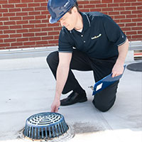 male roofer checking on roof drain