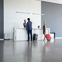 two hotel guests with luggage are checking in at the reception desk