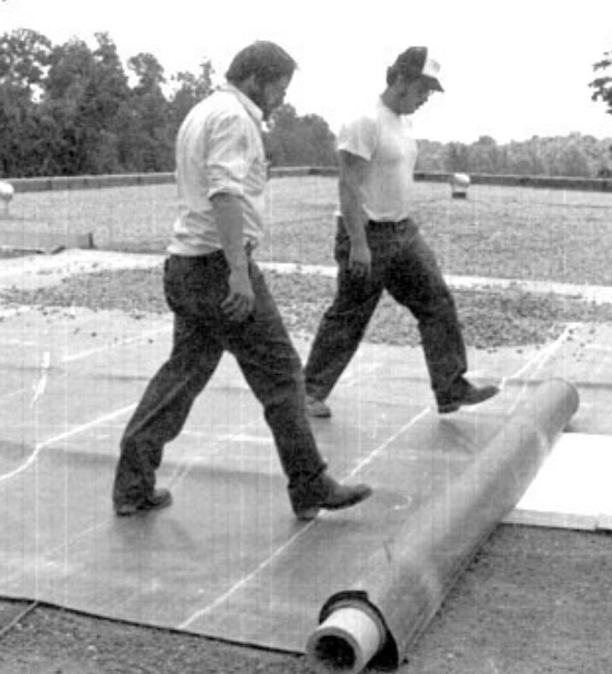 70s photo of roofers rolling EPDM membrane