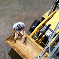 centimark associate is sitting in a tractor bucket during hurricane ida aftermath