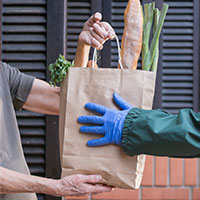 centimark associate is handing a  bag with food to a senior citizen 