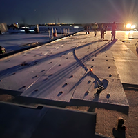 commercial roofers working on the roof at night to avoid heat exhaustion during a heat wave